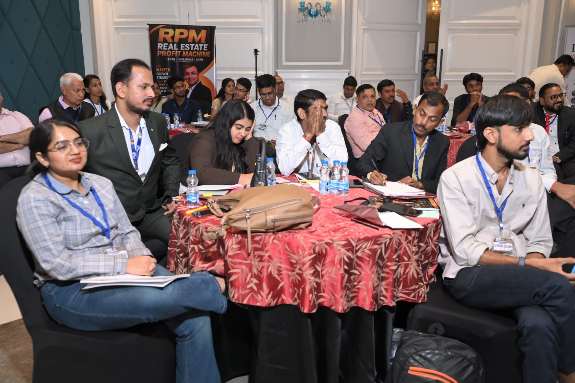 Attendees taking notes at a table beside the RPM banner